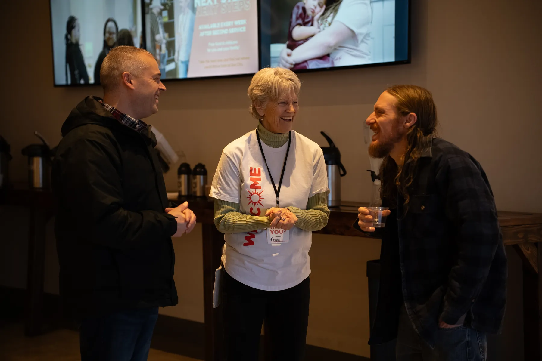 A welcome team member laughing with guests at Sun City Church